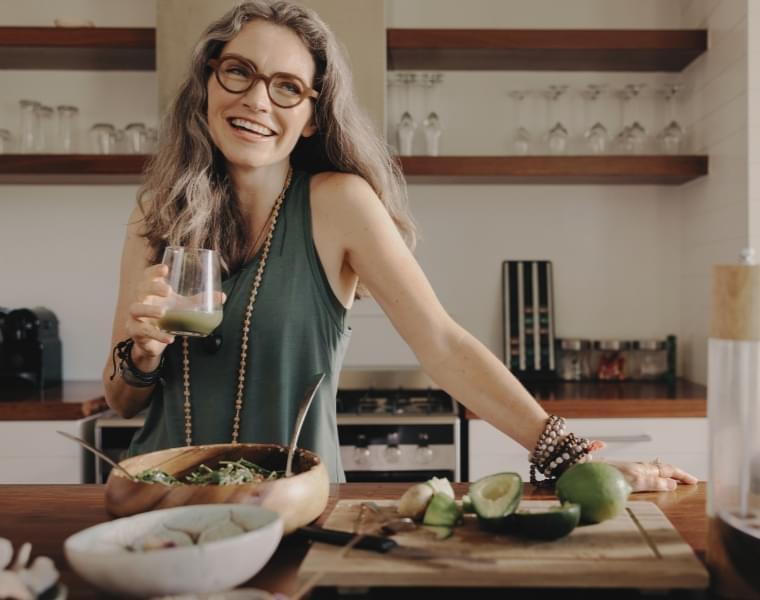 Woman enjoying liminal shake in a modern kitchen with fresh vegetables and healthy ingredients on the counter small